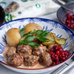 Tallrik med köttbullar, gräddsås, rårörda lingon, potatis och persilja.