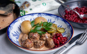 Tallrik med köttbullar, gräddsås, rårörda lingon, potatis och persilja.