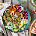 Bowl med anammas falafel, hummus, harissarostade morötter, granatäpplekärnor, silverlök, avokado och pistagenötter.